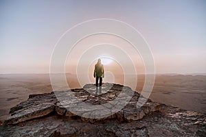 Alone man in israel negev desert admires the view of sunrise. Young male person stands on the edge of the cliff