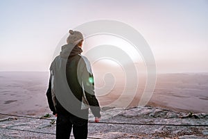 Alone man in israel negev desert admires the view of sunrise. Young male person stands on the edge of the cliff