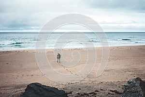 Alone man tourist with backpack goes to the ocean. Melancholic authentic nord landscape