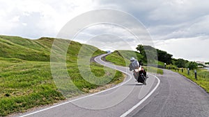 Alone motorcyclist rides along a narrow road