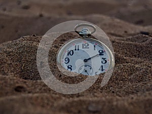 Alone Old pocket watch in the sand