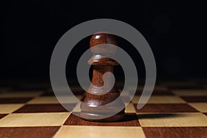 Alone pawn on chess desk against dark background