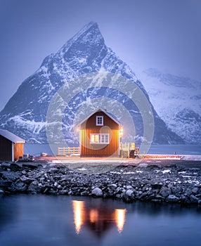 Alone rorbu on sea coast and snow covered mountain at night