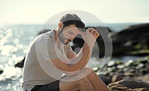 Alone sad man sitting on a beach