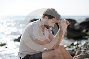 Alone sad man sitting on a beach