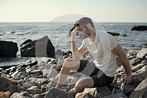 Alone sad man sitting on a sea beach