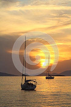 Alone sailboat at sunset. Atmospheric seascape with orange sun.