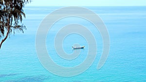 Alone small boat on clean blue sea surface. Traditional thai wooden boat sailing in calm open sea in hot summer day