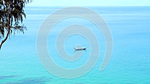 Alone small boat on clean blue sea surface. Traditional thai wooden boat sailing in calm open sea in hot summer day