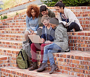 Alone we are smart, together we are brilliant. a group of students sitting outside while on campus.