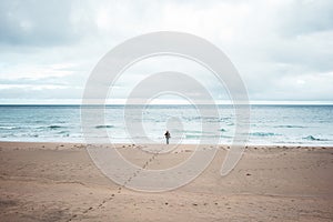 Alone tourist with backpack walks along a deserted beach to the ocean