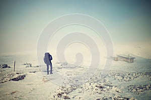 Alone tourist with big backpack and snowshoes walking on snowy path to fog. National park Alps park in Italy. Fogy winter weather.