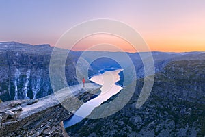 Alone tourist on Trolltunga rock - most spectacular and famous scenic cliff in Norway