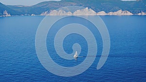 Alone white boat sailing in the deep blue mediterranean sea. Picturesque contours of greek coastlie at horizon