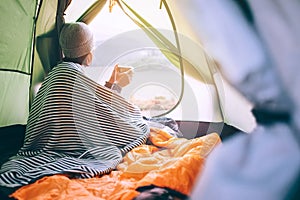 Alone Woman drinks hot tea in camping tent and enjoy with autumn