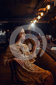 Alone woman with glass of wine sitting in bar