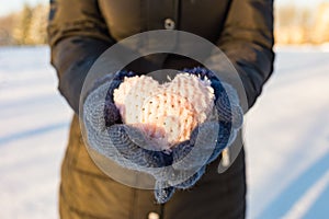 Alone Woman hands in blue gloves holding soft heart. Winter park valentines day time.Close up