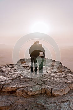 Alone young couple of man and women with backpack in israel negev desert admires the view of sunrise.