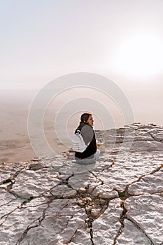 Alone young girl with backpack in israel negev desert admires the view of sunrise. Young female person stands on the edge