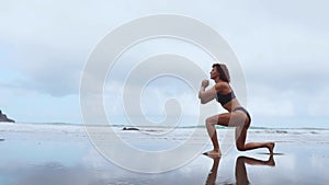 Along the ocean female exercisers performing lunges alternating each leg on the background of rocks and water. Training