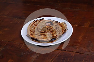 Aloo Paratha / Indian Potato stuffed Flat bread in white plate. on wooden table