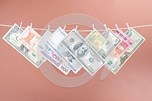 Alot  dollar bills is hanging on a rope with wooden clothespin isolated on brown background. photo