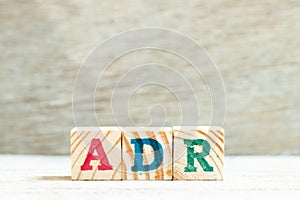 Alphabet block in word ADR Abbreviation of adverse drug reaction on wood background