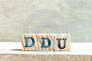 Alphabet block in word DDU (abbreviation of Delivered Duty Unpaid) on wood background