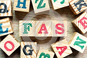 Alphabet block in word FAS abbreviation of Free alongside with another on wood background