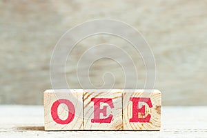 Alphabet block in word OEE abbreviation of overall equipment effectiveness on wood background