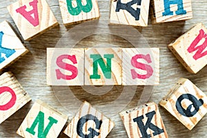 Alphabet block in word SNS abbreviation of Social Networking Site or sorry not sorry with another on wood background