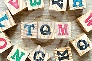 Alphabet block in word TQM Abbreviation of total quality management with another on wood background