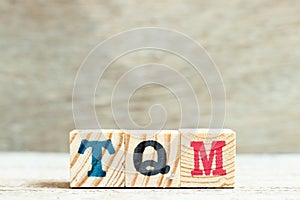 Alphabet block in word TQM Abbreviation of total quality management on wood background