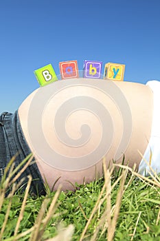 Alphabet blocks spelling BABY on a pregnant belly