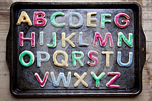 Alphabet in decorated colourful cookies on baking tray, horizontal