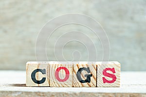 Alphabet block in word COGS Abbreviation of Cost of goods sold on wood background