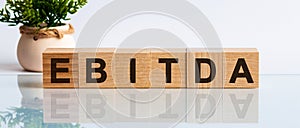 Alphabet letter block in word EBITDA -abbreviation of earnings before interest, taxes, depreciation and amortization - on white