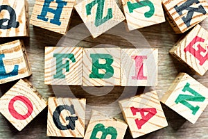 Alphabet block in word FBI Abbreviation of Federal Bureau of Investigation with another on wood background