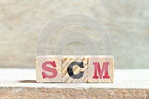 Alphabet block in word SCM Abbreviation of Supply chain management on wood background