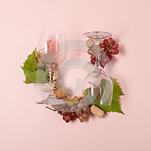 Alphabet. Letter U made of wineglasses with rose and white wine, grapes, leaves and corks lying on pink background. Wine