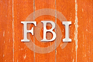 Alphabet in word FBI (Abbreviation of Federal Bureau of Investigation) on old red color wood plate background