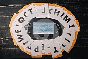 Alphabet letters cards and medical gauze mask on wooden table. Coronavirus Covid 2019 outbreak, selfisolation photo