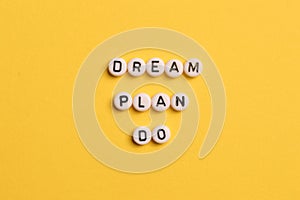 Alphabet letters with text DREAM, PLAN and DO isolated on yellow background