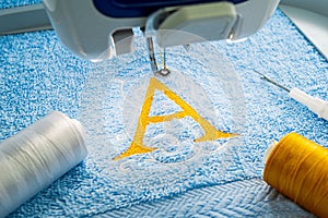 Alphabet logo design on towel in hoop of embroidery machine