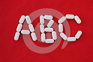 Alphabet made of pills on a red background. Abc from drugs. Vitamins White pills without an inscription. generics, pharmacy and m