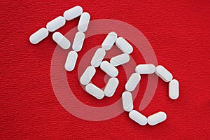 Alphabet made of pills on a red background. Abc from drugs. Vitamins White pills without an inscription. generics, pharmacy and m
