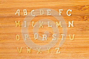 Alphabet pasta placed in alphabetical order on bamboo cutting board