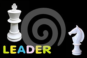 Alphabet sponge rubber of text `LEADER` with chess king and horse standing isolated over black background. Business and leader c