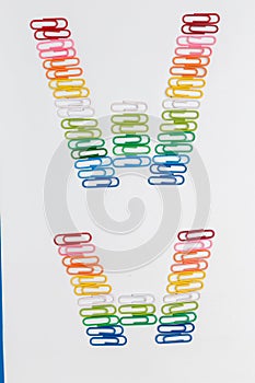 Alphabet W made from color paper clips on white background.