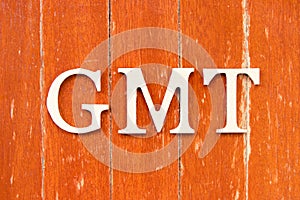 Alphabet in word GMT (abbreviation of Greenwich Mean Time) on old red color wood plate background
